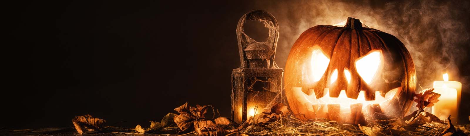 Photo of carved pumpkin lit up from the inside.  Spooky setting.